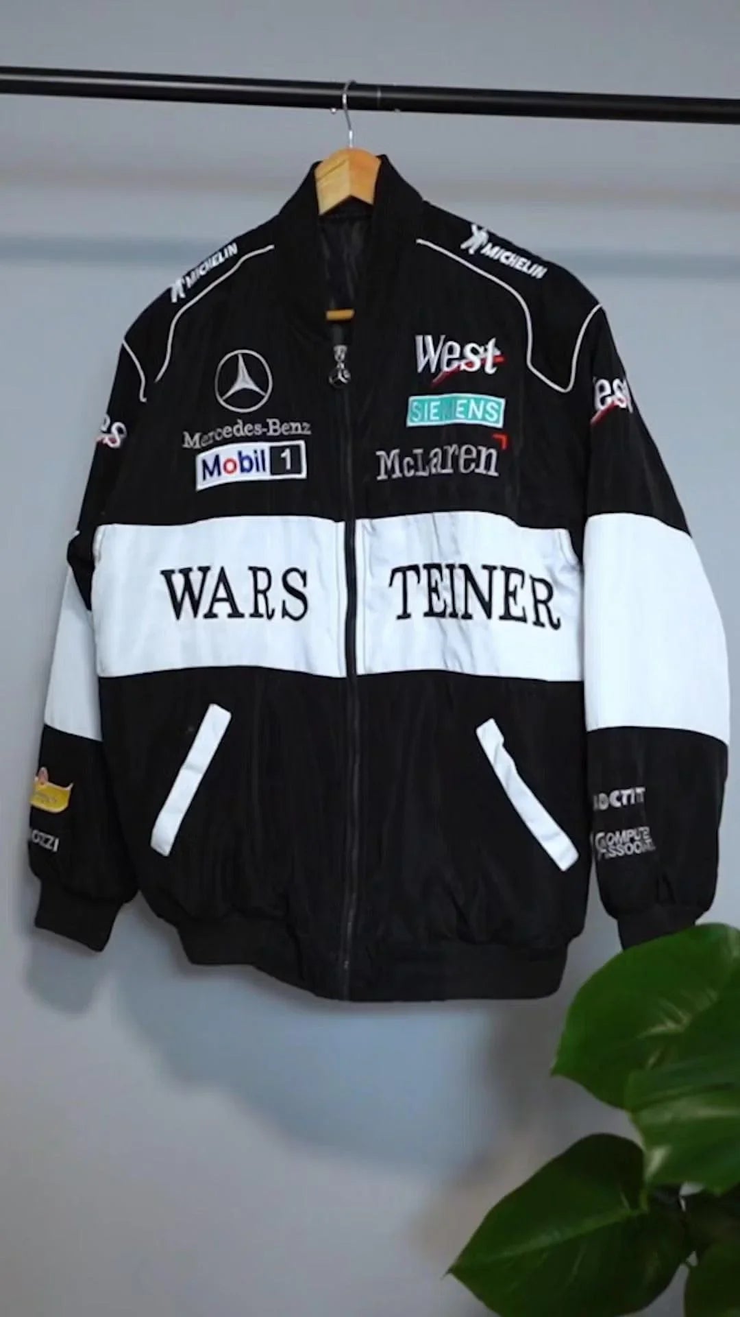 Black and white F1-inspired streetwear jacket with bold graphic logos and embroidered patches.