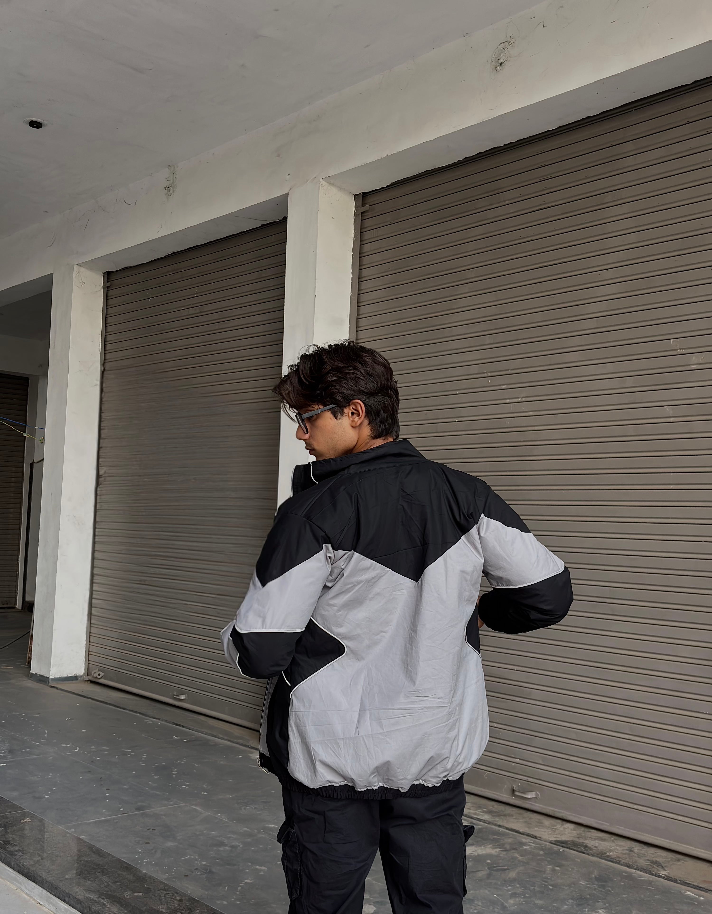 Back profile of the flash-reactive windbreaker designed for night-time streetwear visibility.