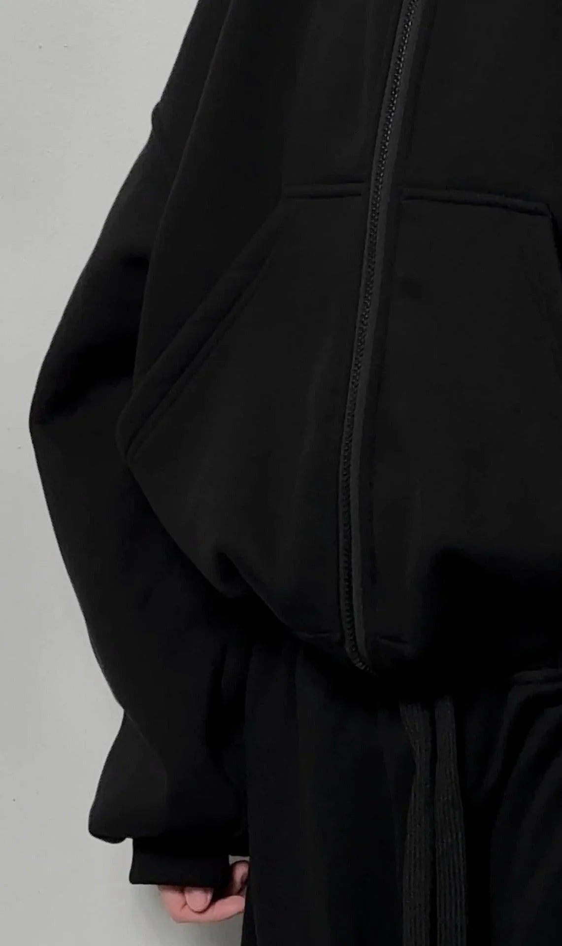 Close-up of oversized black zip-up hoodie with kangaroo pocket and long sleeves