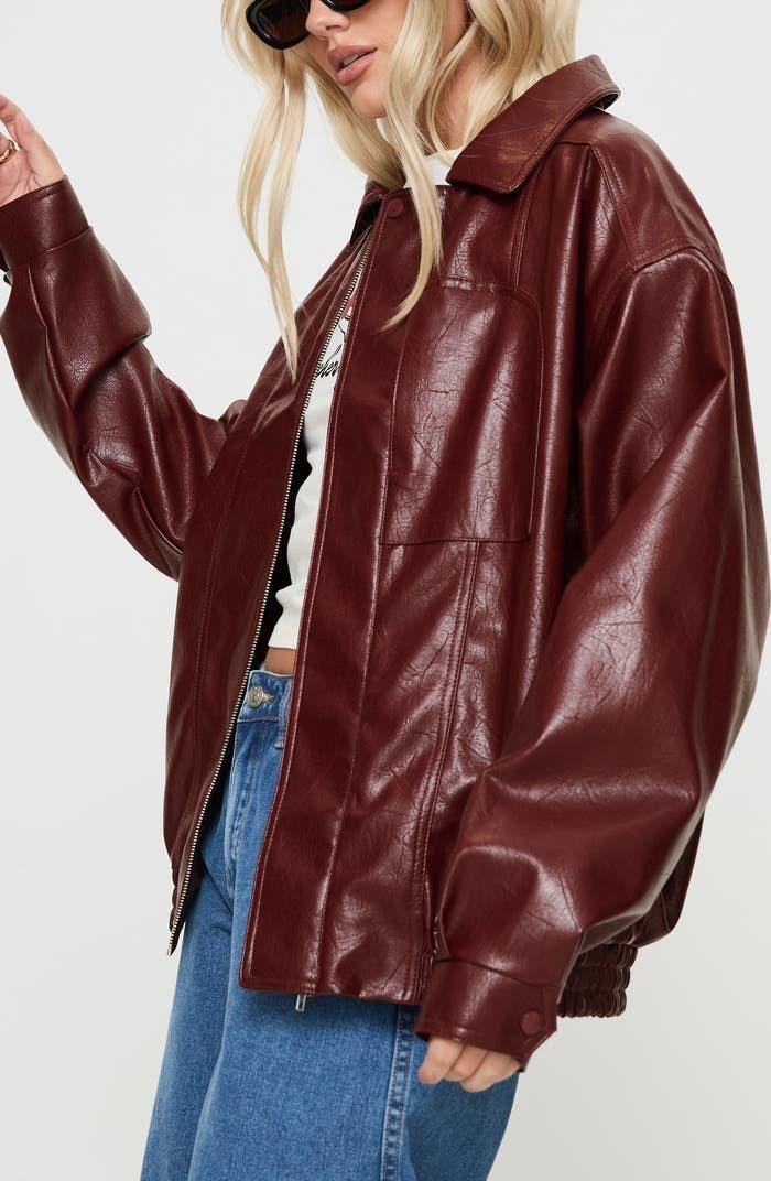 Woman wearing a red burgundy faux leather bomber jacket with jeans and sunglasses