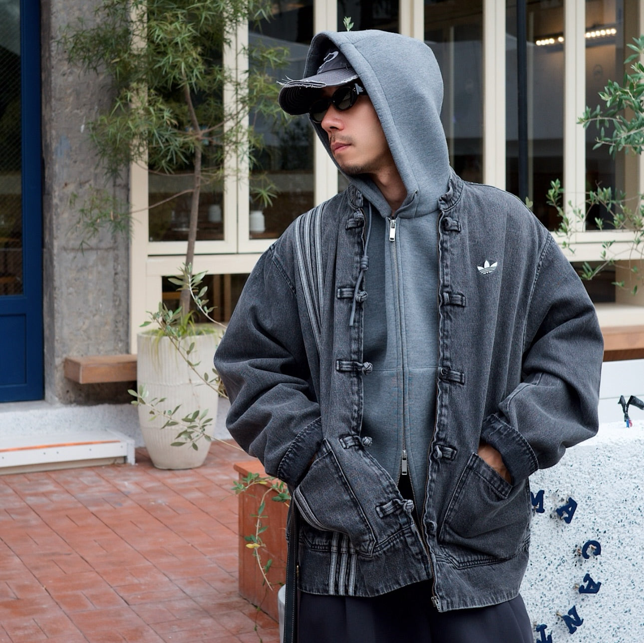 Person wearing a cny denim jacket with a hood, standing outdoors.